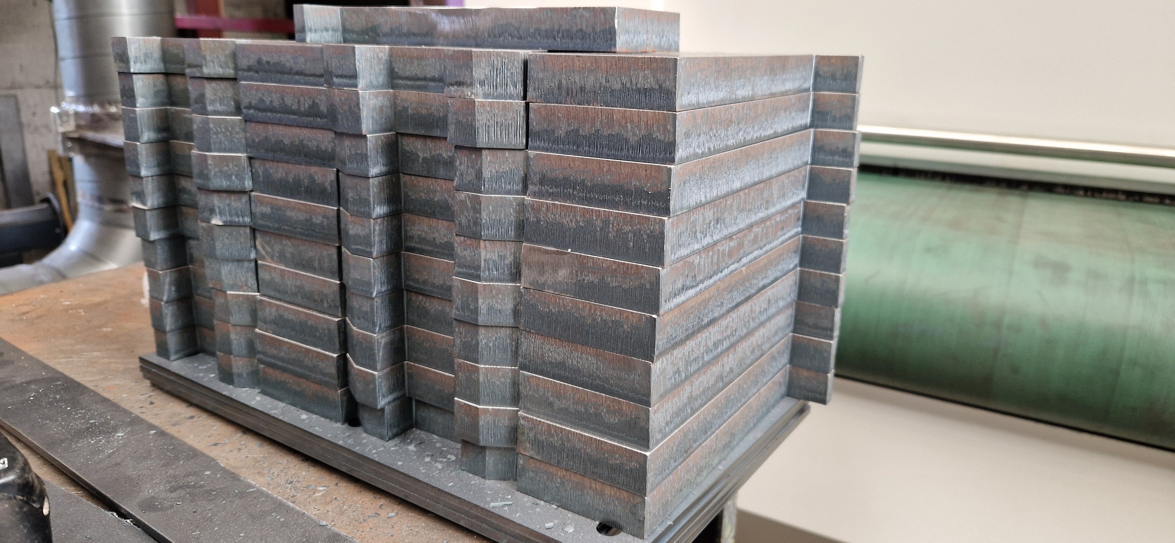 Stacked laser cut steel sections on workbench